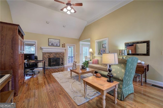 living room with light hardwood / wood-style floors, plenty of natural light, ceiling fan, and a stone fireplace