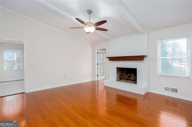 unfurnished living room with a fireplace, hardwood / wood-style floors, vaulted ceiling with beams, and ceiling fan