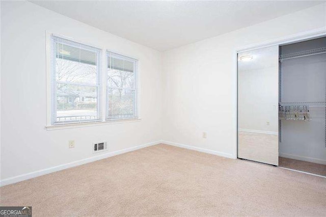 unfurnished bedroom featuring light carpet and a closet