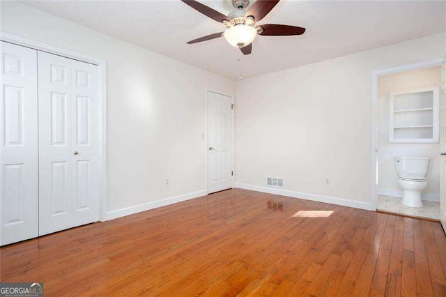 unfurnished bedroom featuring connected bathroom, ceiling fan, and wood-type flooring