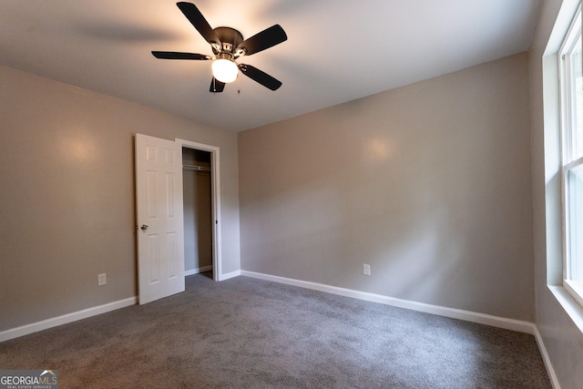 unfurnished bedroom with dark carpet, ceiling fan, and a closet