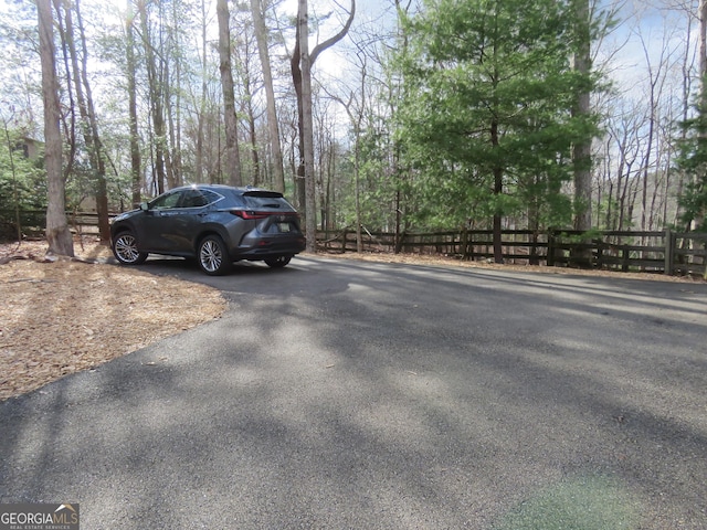 view of parking / parking lot featuring aphalt driveway and fence