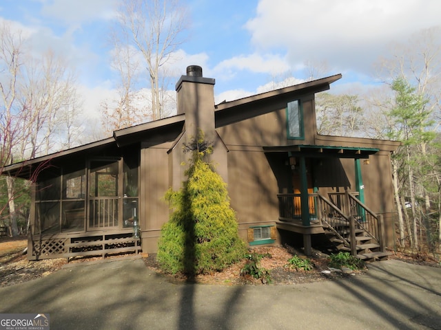 view of property exterior featuring a sunroom and a chimney