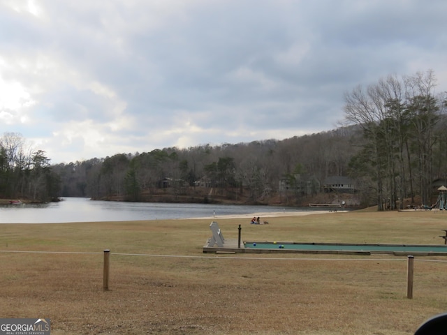 view of community featuring a water view, a lawn, and a wooded view