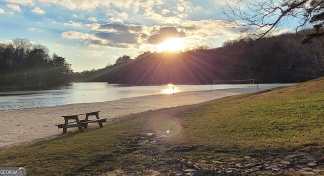 view of community featuring volleyball court, a yard, and a water view