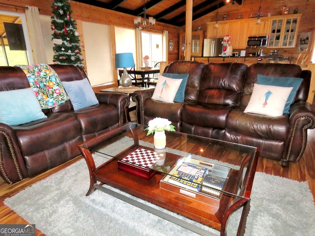 living area with vaulted ceiling with beams, wooden walls, wood finished floors, and a chandelier