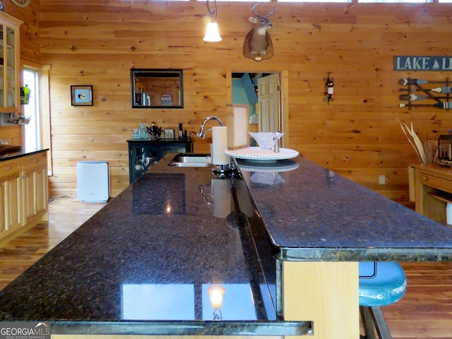 kitchen with a breakfast bar, a large island, glass insert cabinets, a sink, and dark stone counters