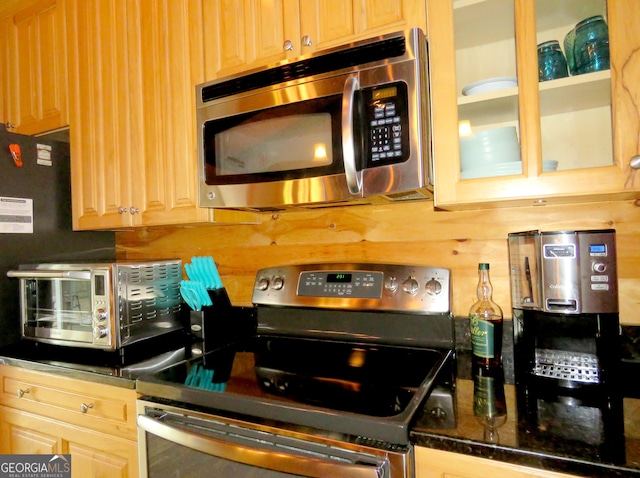 kitchen with a toaster, glass insert cabinets, appliances with stainless steel finishes, light brown cabinetry, and backsplash