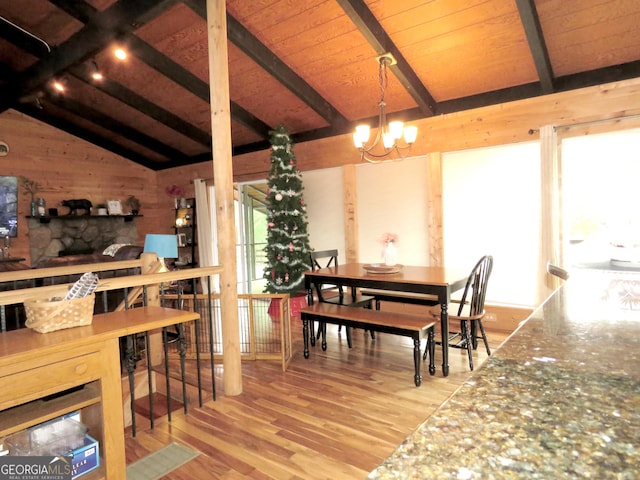 dining space featuring lofted ceiling with beams, wood ceiling, light wood-type flooring, wood walls, and a notable chandelier