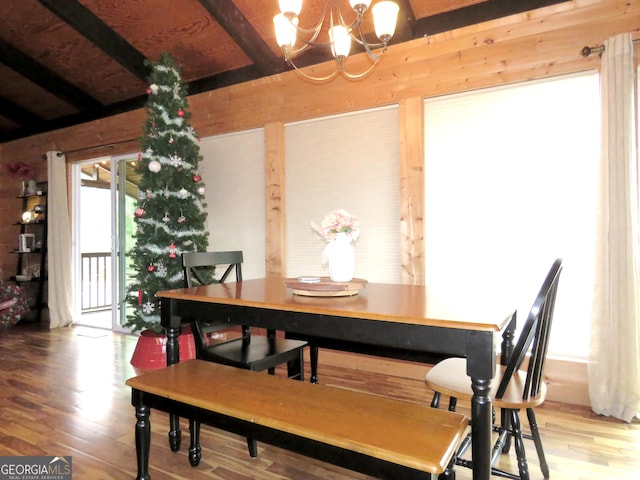 dining area with a notable chandelier, wood finished floors, and beamed ceiling