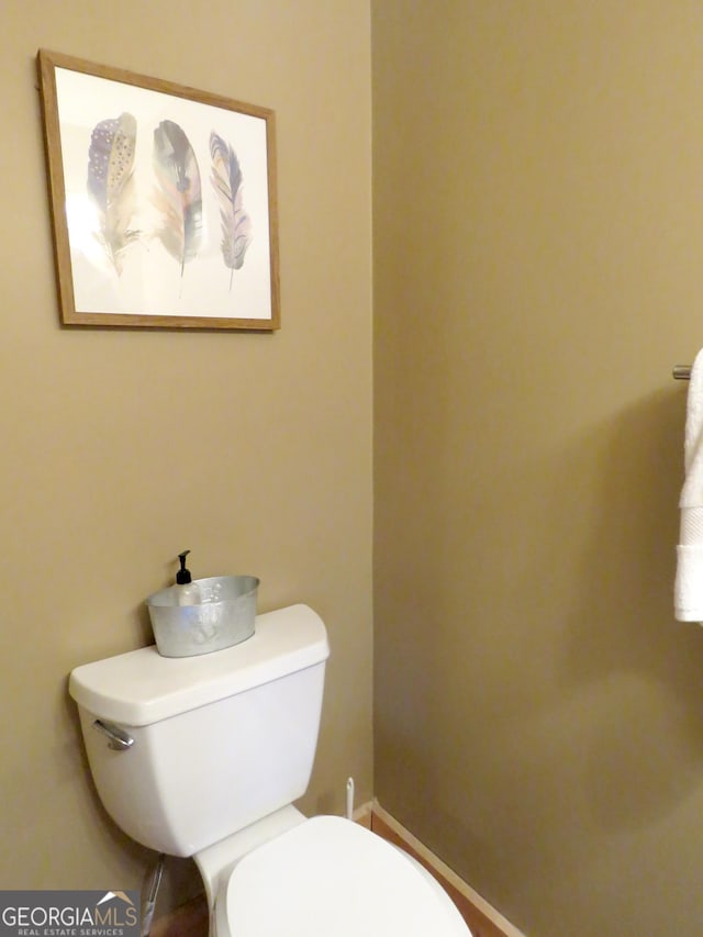 half bath with baseboards and toilet