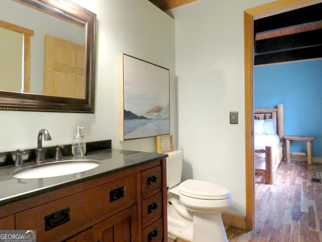 bathroom featuring baseboards, vanity, toilet, and wood finished floors