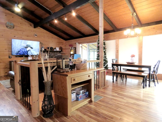 kitchen featuring lofted ceiling with beams, wood walls, pendant lighting, and light wood-style floors