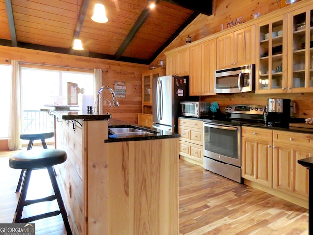 kitchen featuring stainless steel appliances, dark countertops, a kitchen bar, and glass insert cabinets