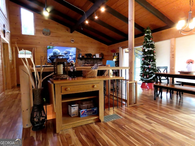 living area with vaulted ceiling with beams, wood walls, wood finished floors, wood ceiling, and rail lighting