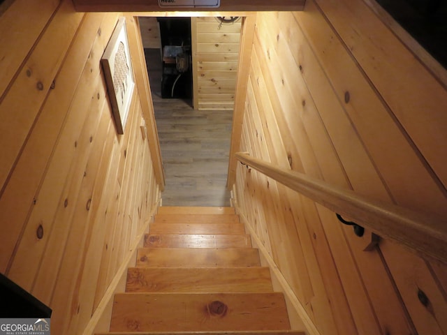 staircase featuring wooden walls and wood finished floors