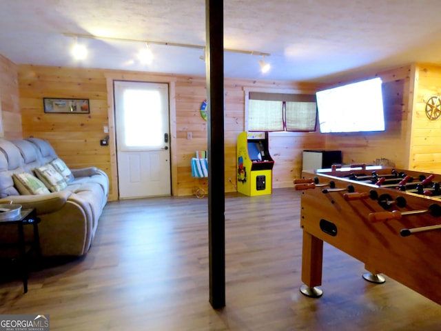 game room featuring wood finished floors, rail lighting, and wooden walls