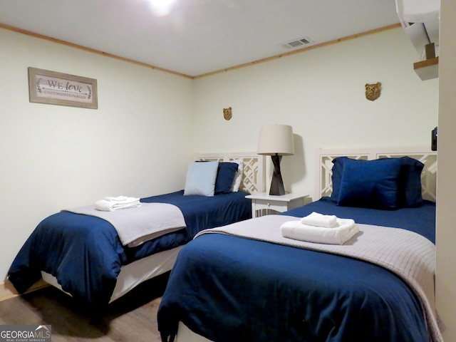 bedroom featuring visible vents, crown molding, and wood finished floors