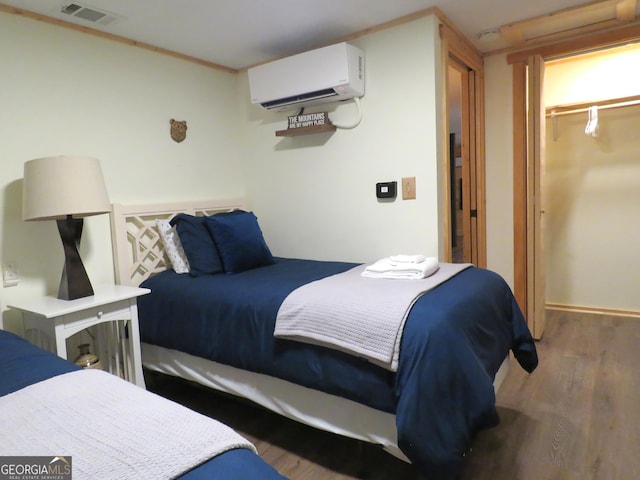 bedroom featuring a walk in closet, dark wood-style flooring, a closet, visible vents, and a wall mounted air conditioner