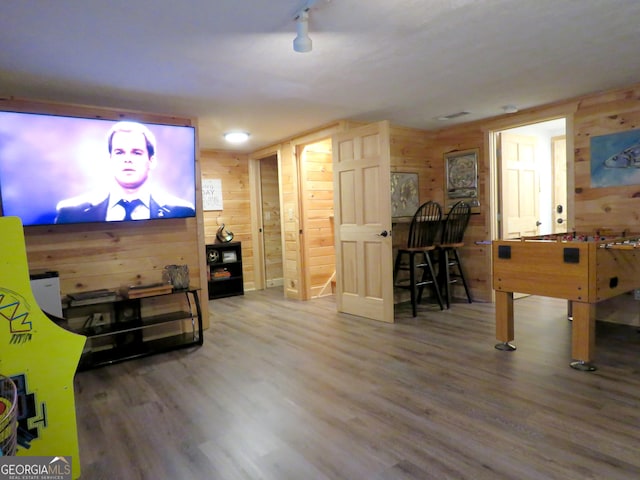 game room with wood walls and wood finished floors