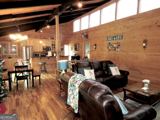 living area featuring a notable chandelier, wooden walls, lofted ceiling with beams, and wood finished floors