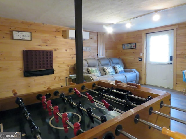 living room with an AC wall unit, rail lighting, and wood walls