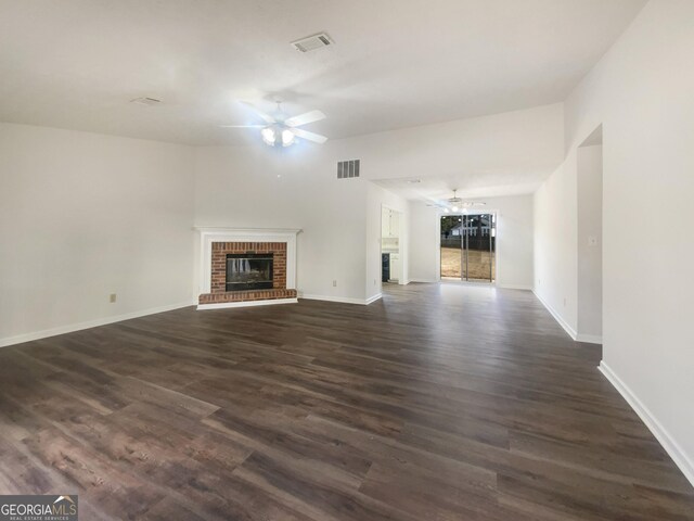 unfurnished living room with visible vents, dark wood-type flooring, a fireplace, and a ceiling fan