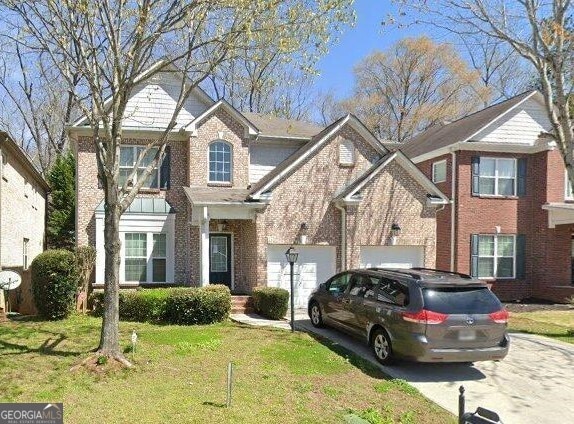 view of front facade with concrete driveway, brick siding, and a front lawn