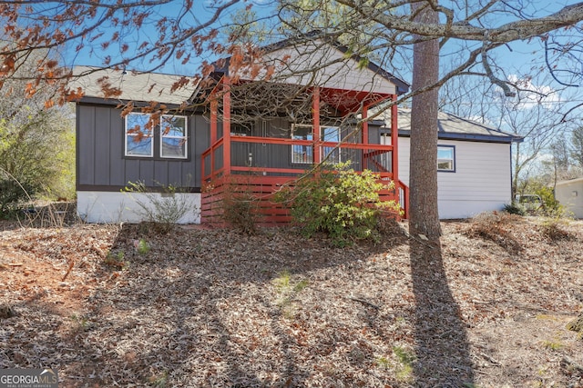 exterior space featuring board and batten siding, covered porch, and roof with shingles