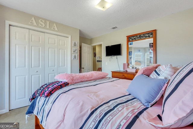 bedroom with a textured ceiling, a closet, and light colored carpet