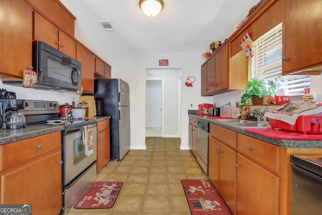 kitchen featuring sink, a textured ceiling, and stainless steel appliances