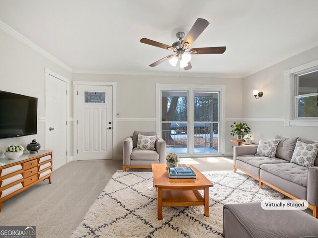 living area featuring light carpet, ornamental molding, and a ceiling fan