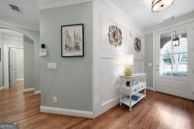 foyer entrance with ornamental molding and hardwood / wood-style floors