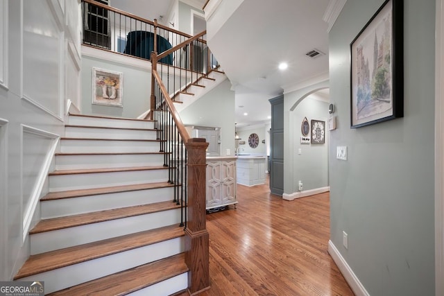 stairway with hardwood / wood-style flooring and ornamental molding