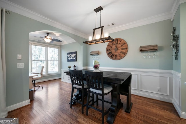 dining room featuring dark wood-type flooring, crown molding, and ceiling fan with notable chandelier