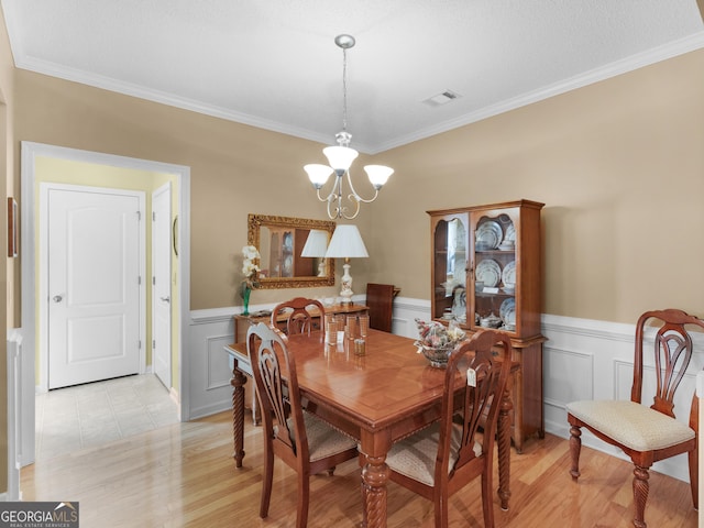509 Carleton Pl, Locust Grove, GA 30248 - dining space featuring a chandelier, ornamental molding, light wood finished floors, a wainscoted wall, and a decorative wall