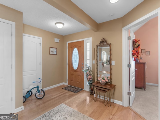 entrance foyer with light wood-type flooring, baseboards, and a textured ceiling