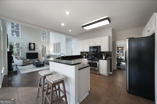 kitchen with open floor plan, appliances with stainless steel finishes, a breakfast bar, and white cabinets