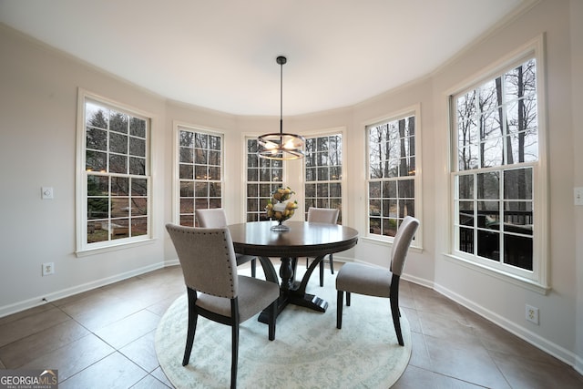 tiled dining area with ornamental molding, a notable chandelier, and baseboards