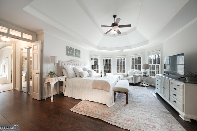 bedroom with dark wood-style floors, ornamental molding, a raised ceiling, and a ceiling fan