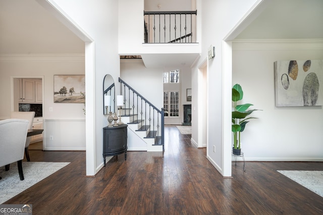 entrance foyer featuring dark wood-type flooring, crown molding, baseboards, and stairs