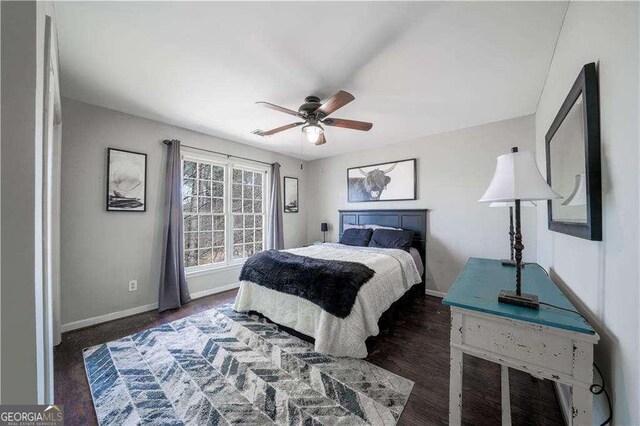 bedroom with dark wood-type flooring, a ceiling fan, and baseboards