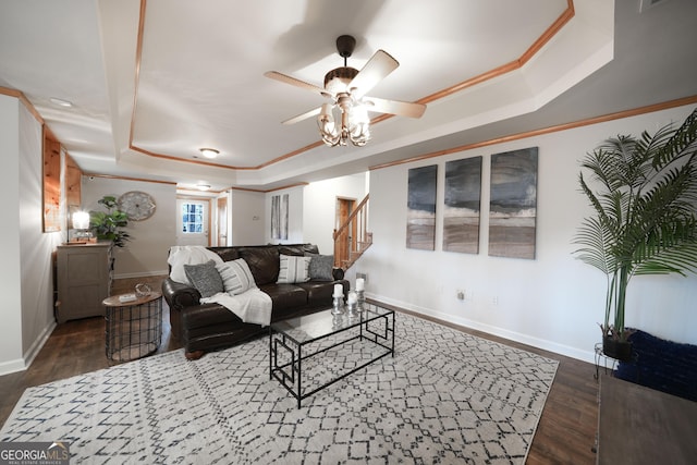 living room with dark wood-style flooring, baseboards, stairs, ornamental molding, and a raised ceiling