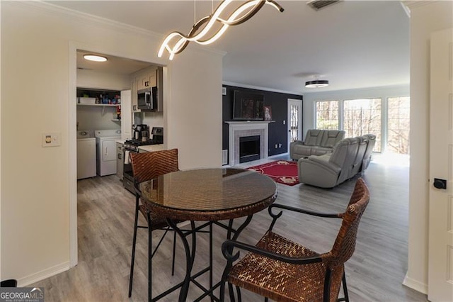709 Berkeley Woods Unit 709, Duluth, GA 30096 - dining space featuring washing machine and dryer, ornamental molding, light wood finished floors, a fireplace, and a chandelier