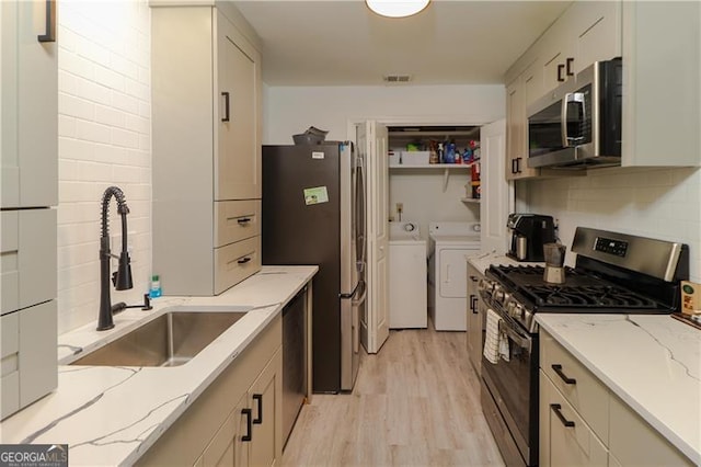 709 Berkeley Woods Unit 709, Duluth, GA 30096 - kitchen featuring appliances with stainless steel finishes, separate washer and dryer, light wood-style flooring, light stone counters, and tasteful backsplash