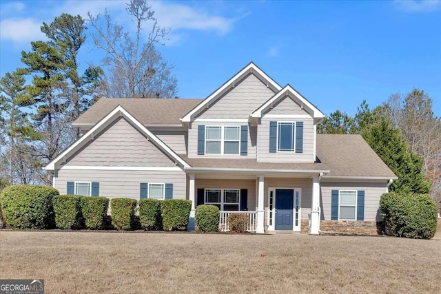 craftsman inspired home with a porch, a front yard, and roof with shingles