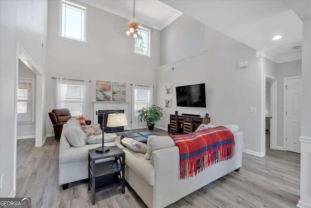 living area with ornamental molding, a fireplace, light wood-style floors, and baseboards