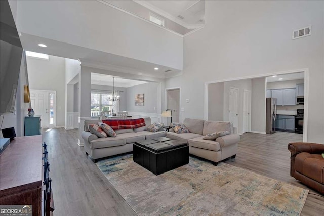living room with wood finished floors, visible vents, and an inviting chandelier