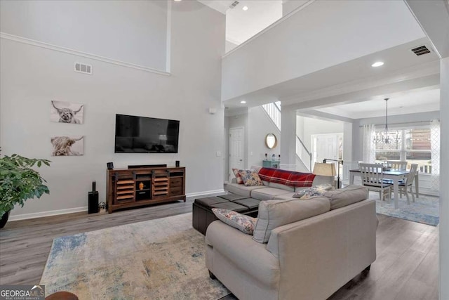 living area featuring a chandelier, visible vents, baseboards, and wood finished floors