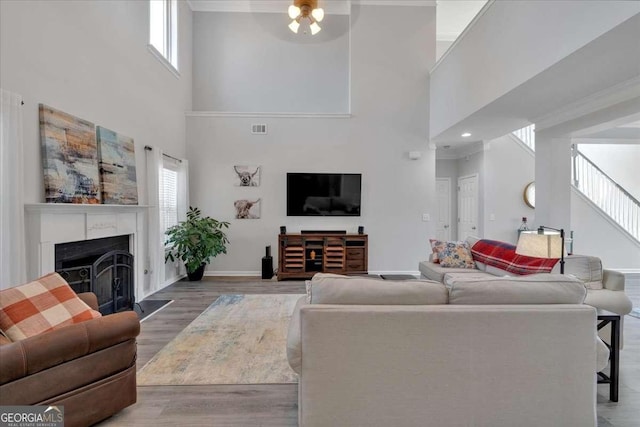 living room with a fireplace, visible vents, stairway, wood finished floors, and baseboards